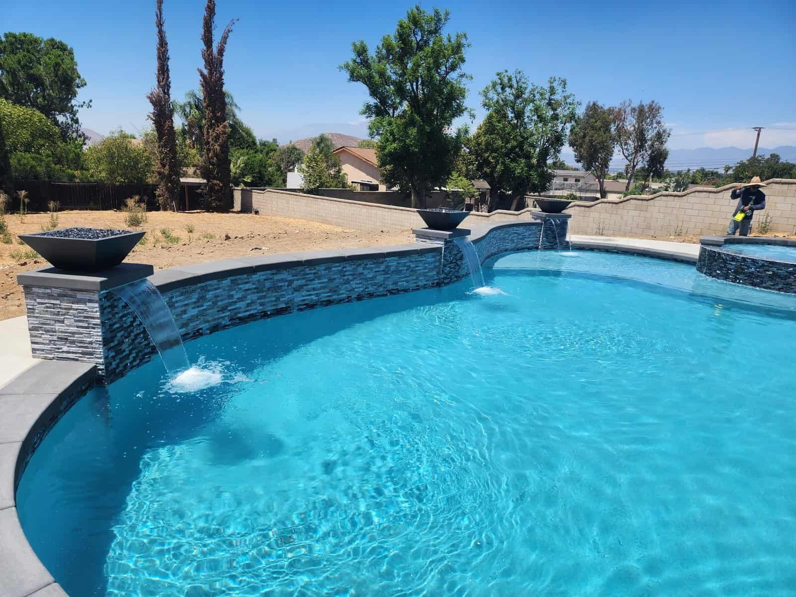 Custom backyard pool with waterfalls and modern design in a sunny outdoor setting.