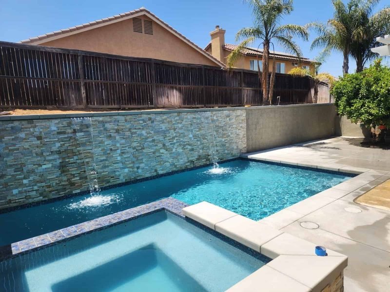 Pool with waterfall feature and modern backyard patio.